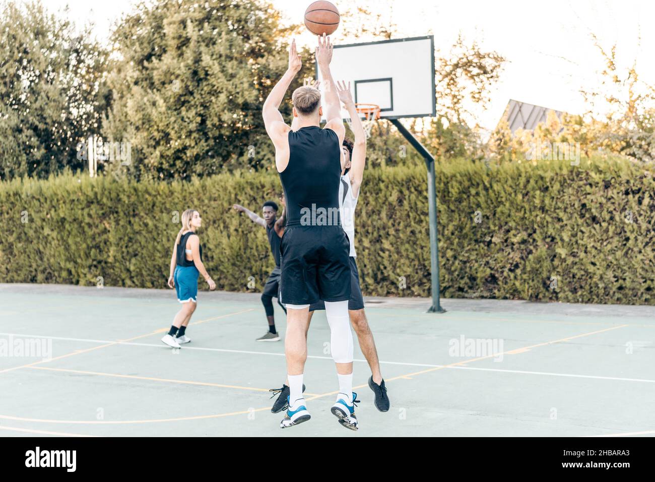 Eine Gruppe von Freunden, die auf einem öffentlichen Platz im Freien Basketball spielen Stockfoto