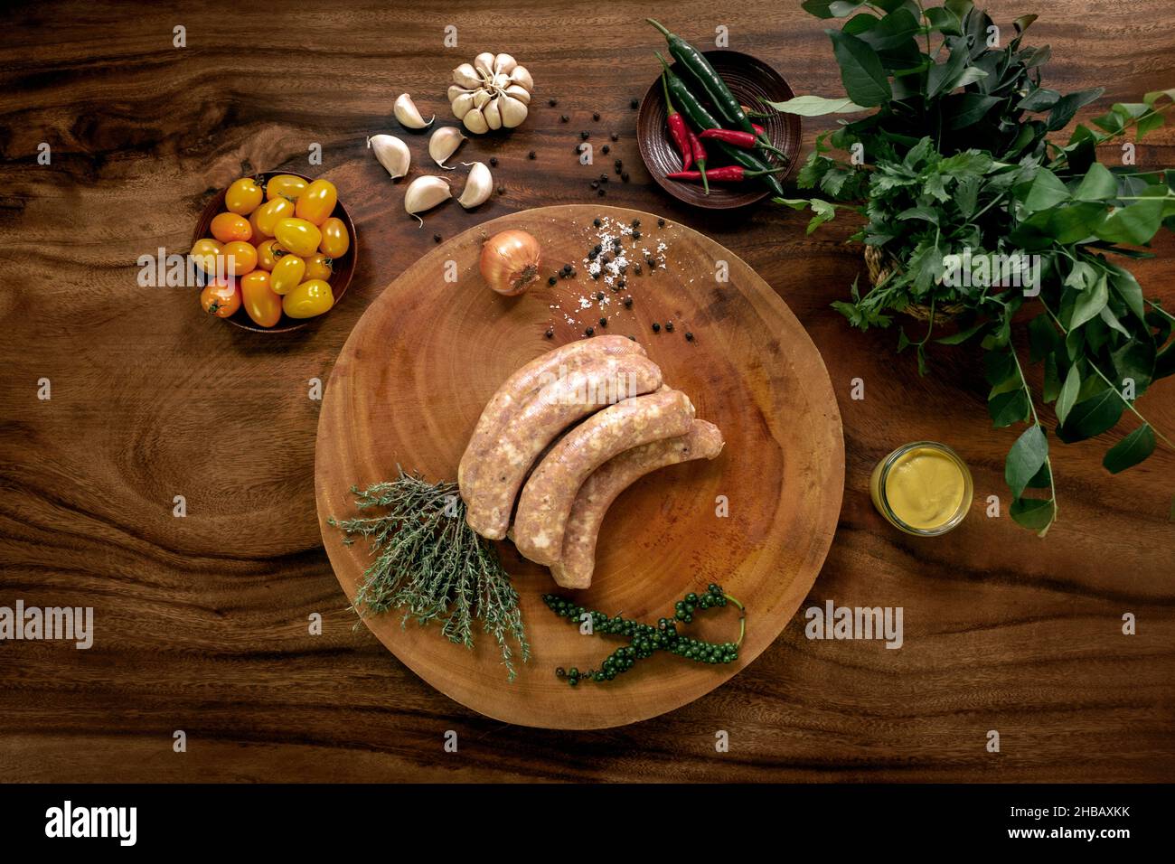 Traditionelle frische hausgemachte englische rohe Schweinefleischwürste auf rustikalem Holztisch mit natürlichen Zutaten Stockfoto