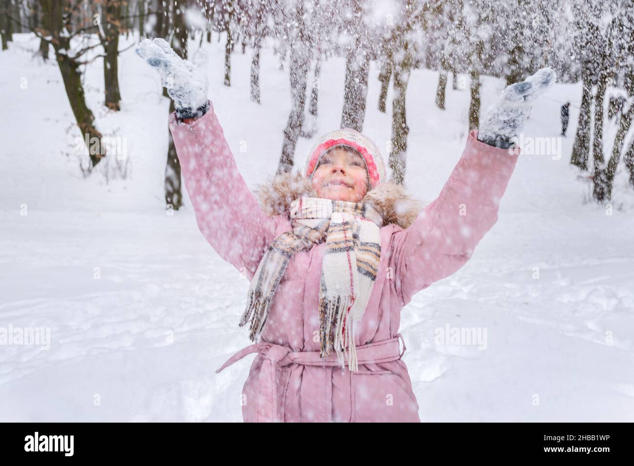 Ein kleines Mädchen hat Spaß beim Spielen mit Schnee in der Natur. Stockfoto