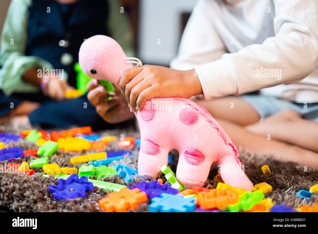 Zwei nicht erkennbare kleine Geschwister Kinder spielen mit rosa Dinosaurier Spielzeug zu Hause - Konzept der Entwicklung von Kindern und Kinderspaß während der Ferien. Stockfoto