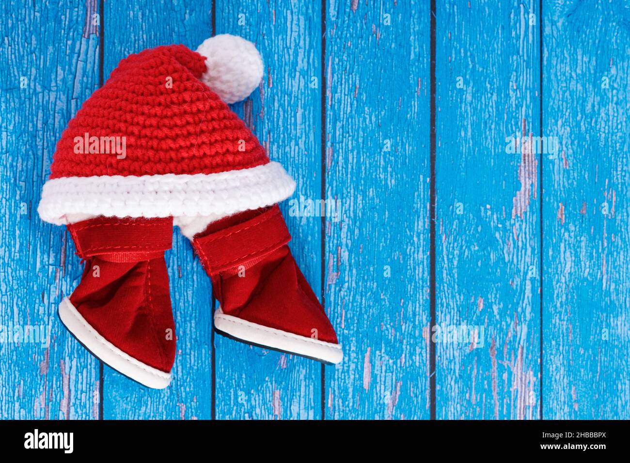 weihnachtsmann Hut mit roten Stiefeln auf blauem Holzhintergrund Stockfoto