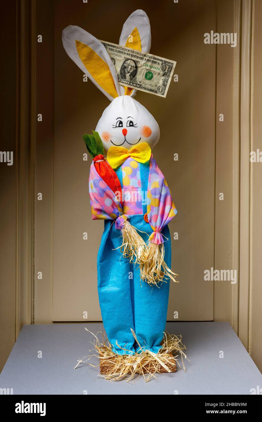 Gefülltes glückliches Kaninchen mit 1 einer zerknitterten US-Dollar-Banknote zwischen den Ohren, Stockfoto