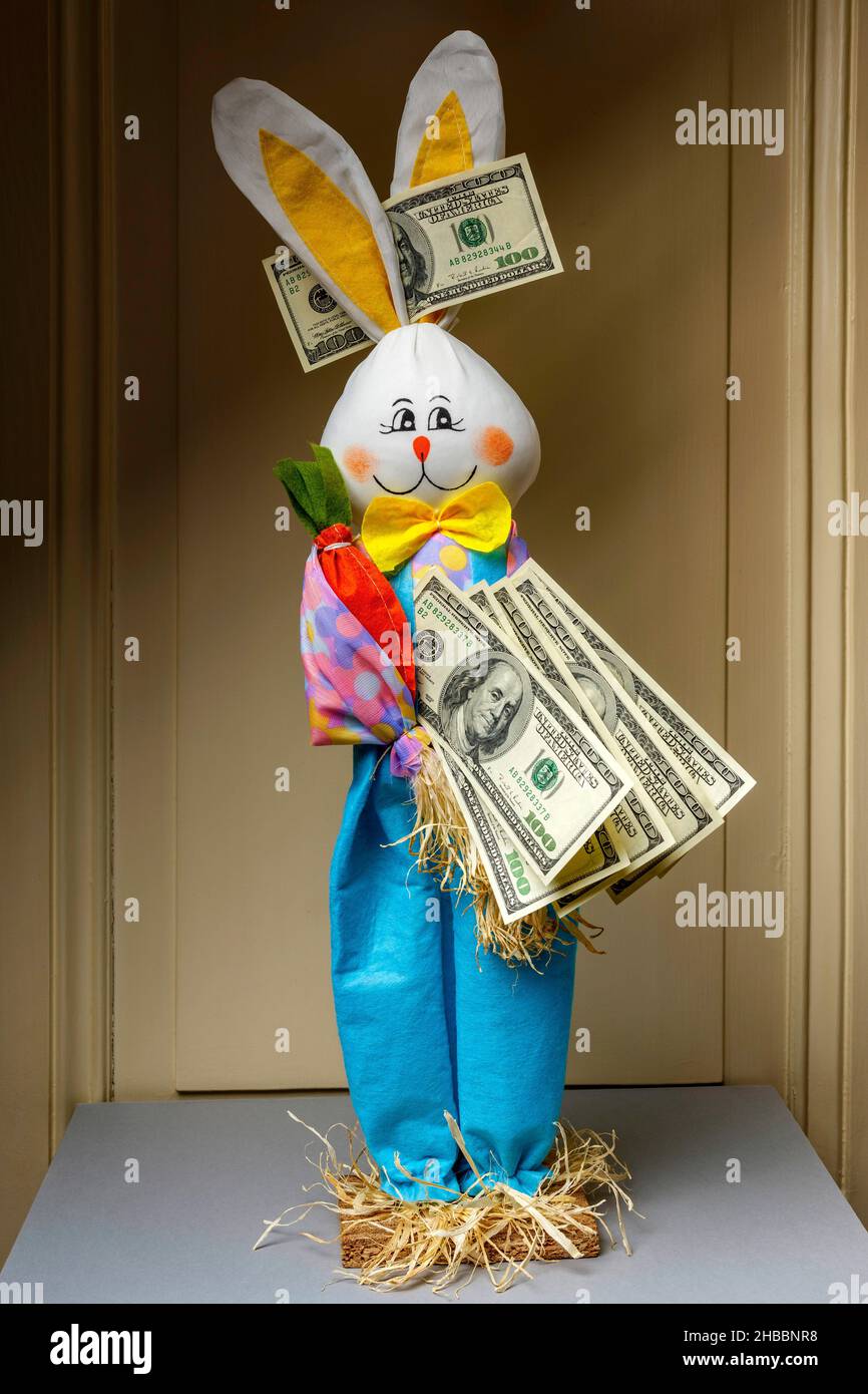 Gefülltes glückliches Kaninchen mit einem Fächer von hundert US-Dollar-Banknoten und 1 einer US-Dollar-Banknote zwischen den Ohren, Stockfoto