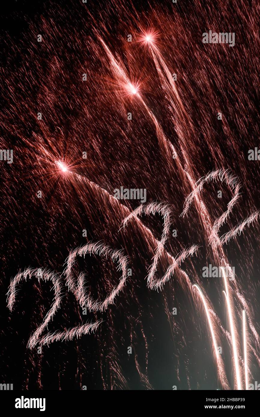 Frohes Neues Jahr 2022. Funkelnde brennende Zahlen Jahr 2022 mit Feuerwerk auf schwarzem Hintergrund. Stockfoto