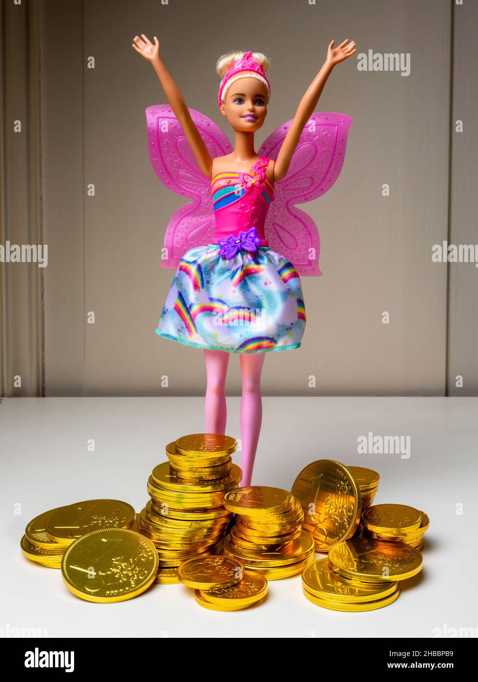 Barbie-Puppe, die Arme hebt, Stapel von Pralinen mit geprägter Euro-Münze goldene Folie verpackt, Stockfoto
