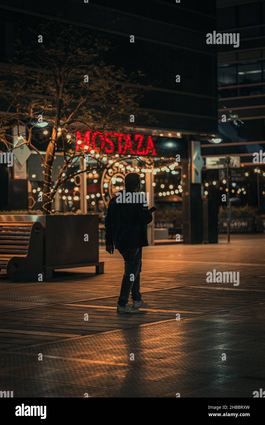 BUENOS AIRES, ARGENTINIEN - 23. Sep 2021: Eine vertikale Aufnahme eines Mannes, der nachts in der Nähe von Mostaza in Puerto Madero, Buenos Aires, Argentinien, läuft Stockfoto