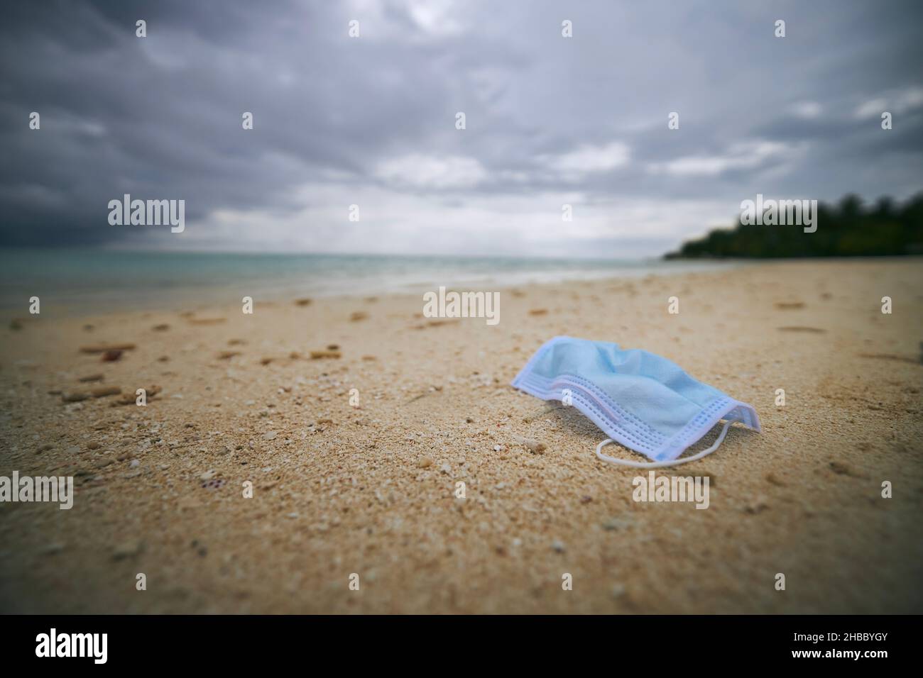 Verlassene und gebrauchte Schutzmaske am Sandstrand. Themen Covid-19, Umweltverschmutzung und Umweltprobleme. Stockfoto