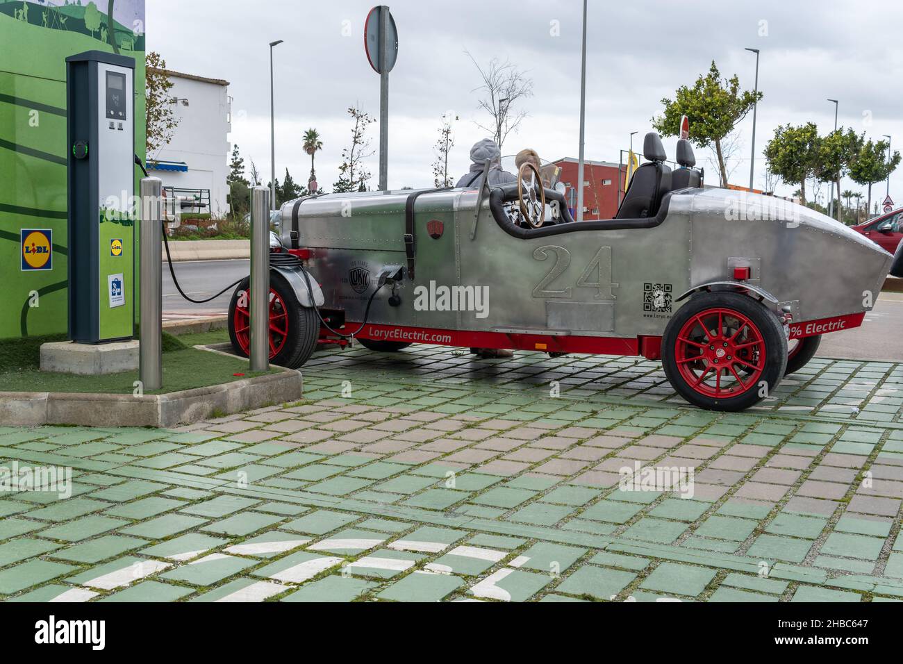 Campos, Spanien, dezember 11 2021: Lorycs modernes Elektroauto im Design von 1920s an einer elektrischen Ladestelle auf dem Parkplatz eines Lidl-Kettensupermar Stockfoto
