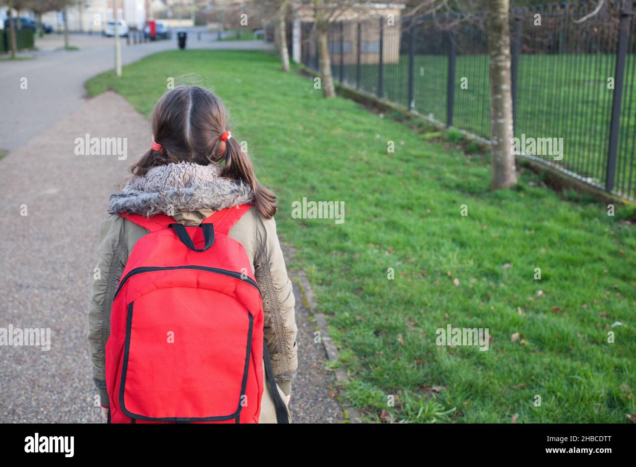 Ein Schulmädchen mit ihrer Schultasche, das allein von der Schule in Großbritannien nach Hause geht Stockfoto