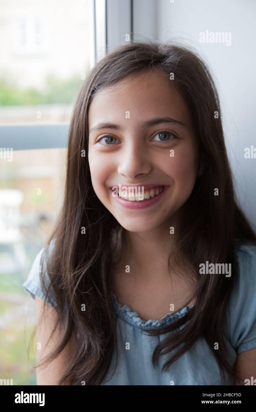 Ein Porträt in einem Fenster eines Mädchens aus gemischter Rasse mit einem großen Lächeln, das kaukasisch, asiatisch und schwarz ist Stockfoto