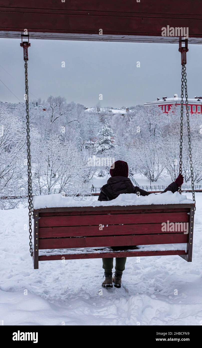 Frau im Park im Winter sitzt auf einer Schaukel. Hochwertige Fotos Stockfoto