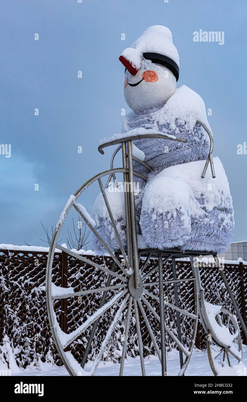 Figur eines dekorativen Schneemanns auf einem großen Fahrrad. Hochwertige Fotos Stockfoto