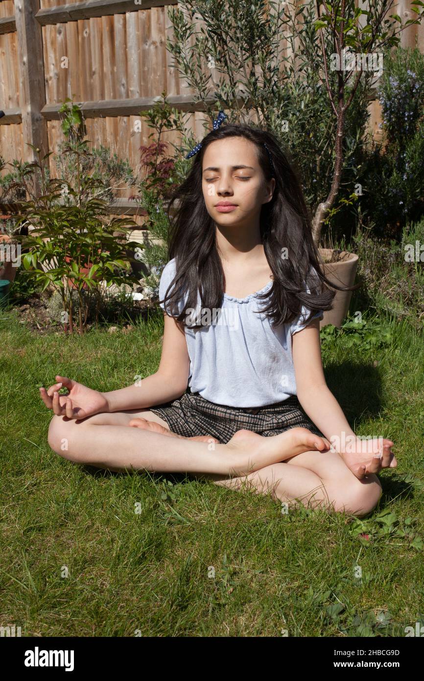 Ein Mädchen meditiert in der Sonne in ihrem Garten Stockfoto