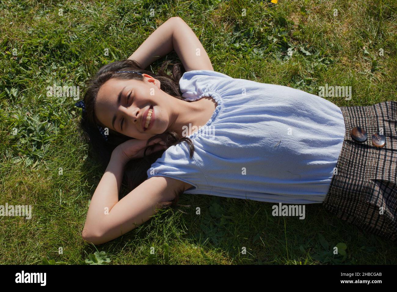 Ein Porträt eines Mädchens, das in der Sonne auf dem Rücken lachend liegt Stockfoto