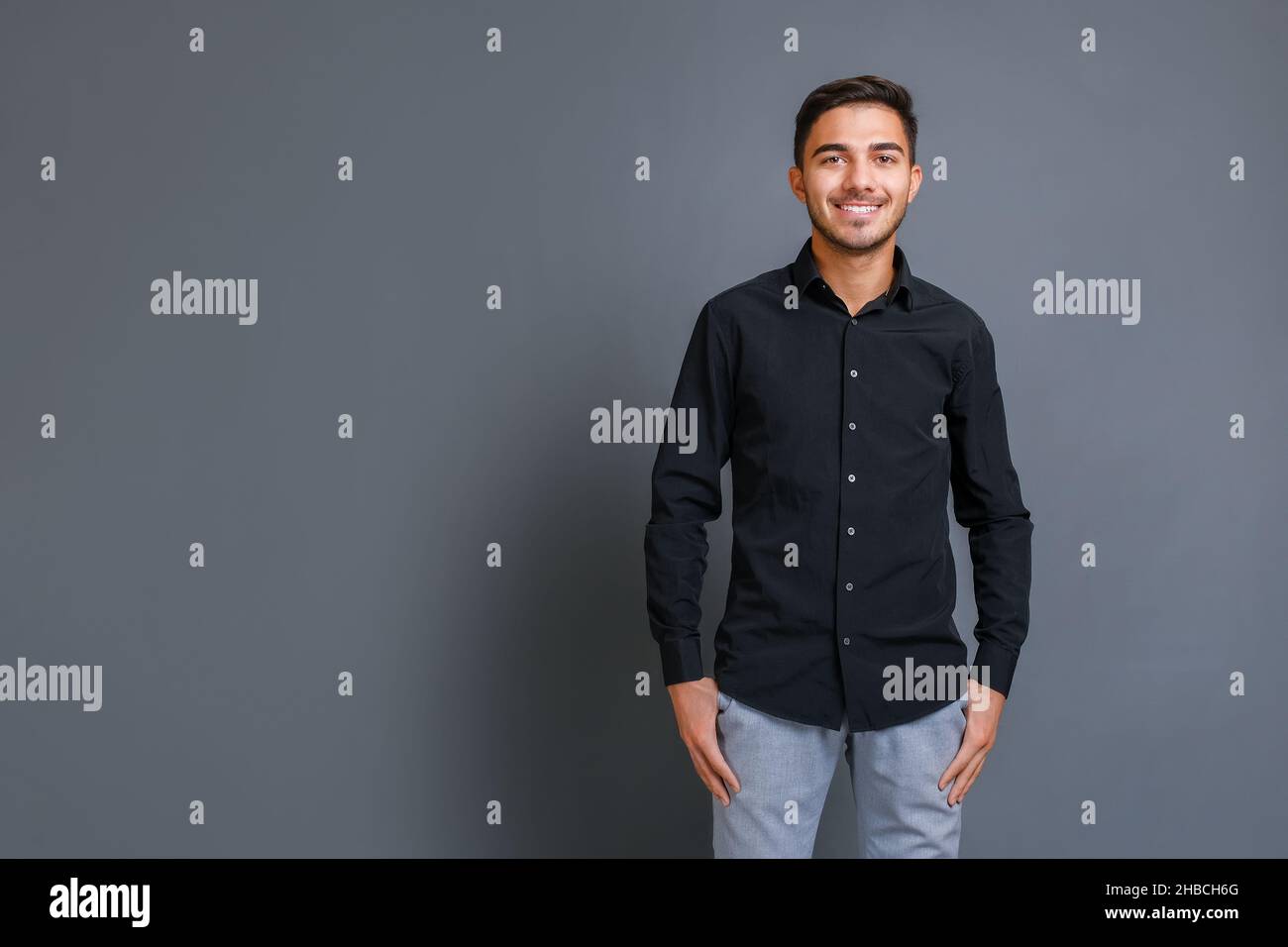 Porträt eines lächelnden, gutaussehenden und selbstbewussten jungen Geschäftsmannes in schwarzem Hemd Stockfoto