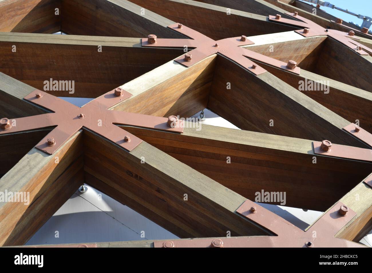 Nahaufnahme der stabilen dreieckigen Verriegelungsstruktur aus Holzbalken, die mit großen Eisenmuttern fixiert ist. Details. Stockfoto