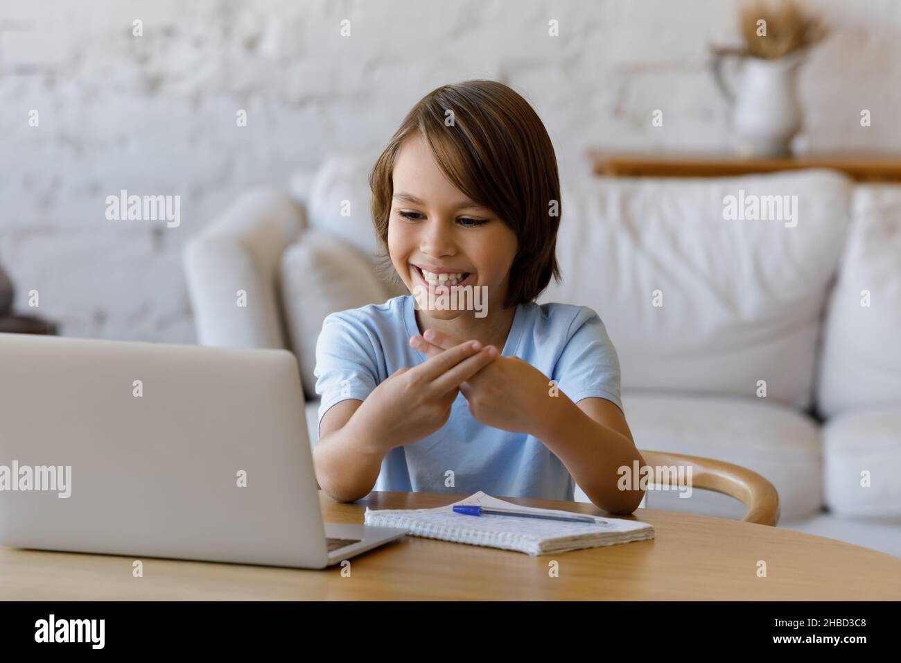 Fröhlicher Teenager, der Gebärdensprache verwendet und per Videoanruf kommuniziert. Stockfoto