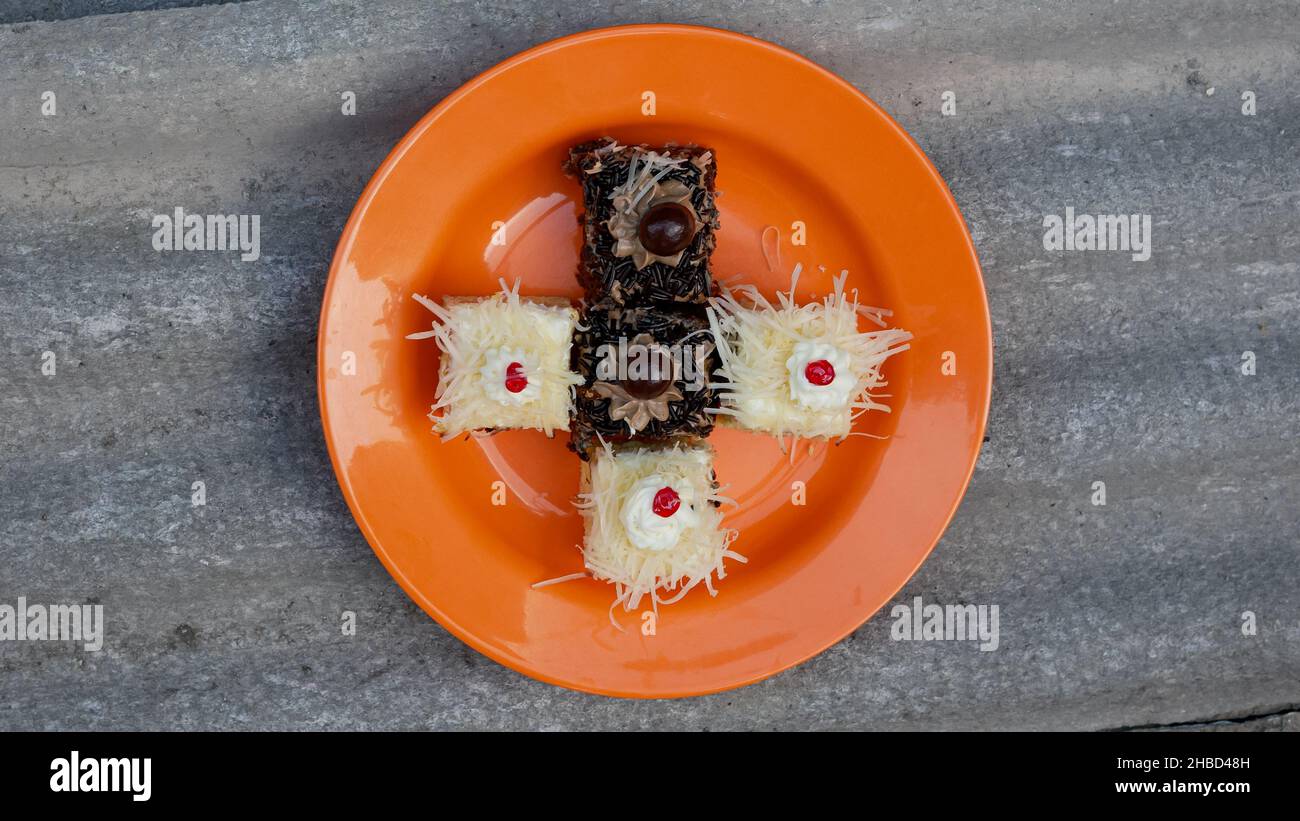 Mini-Törtchen mit Käse und Schokolade auf orangefarbenem Teller Stockfoto