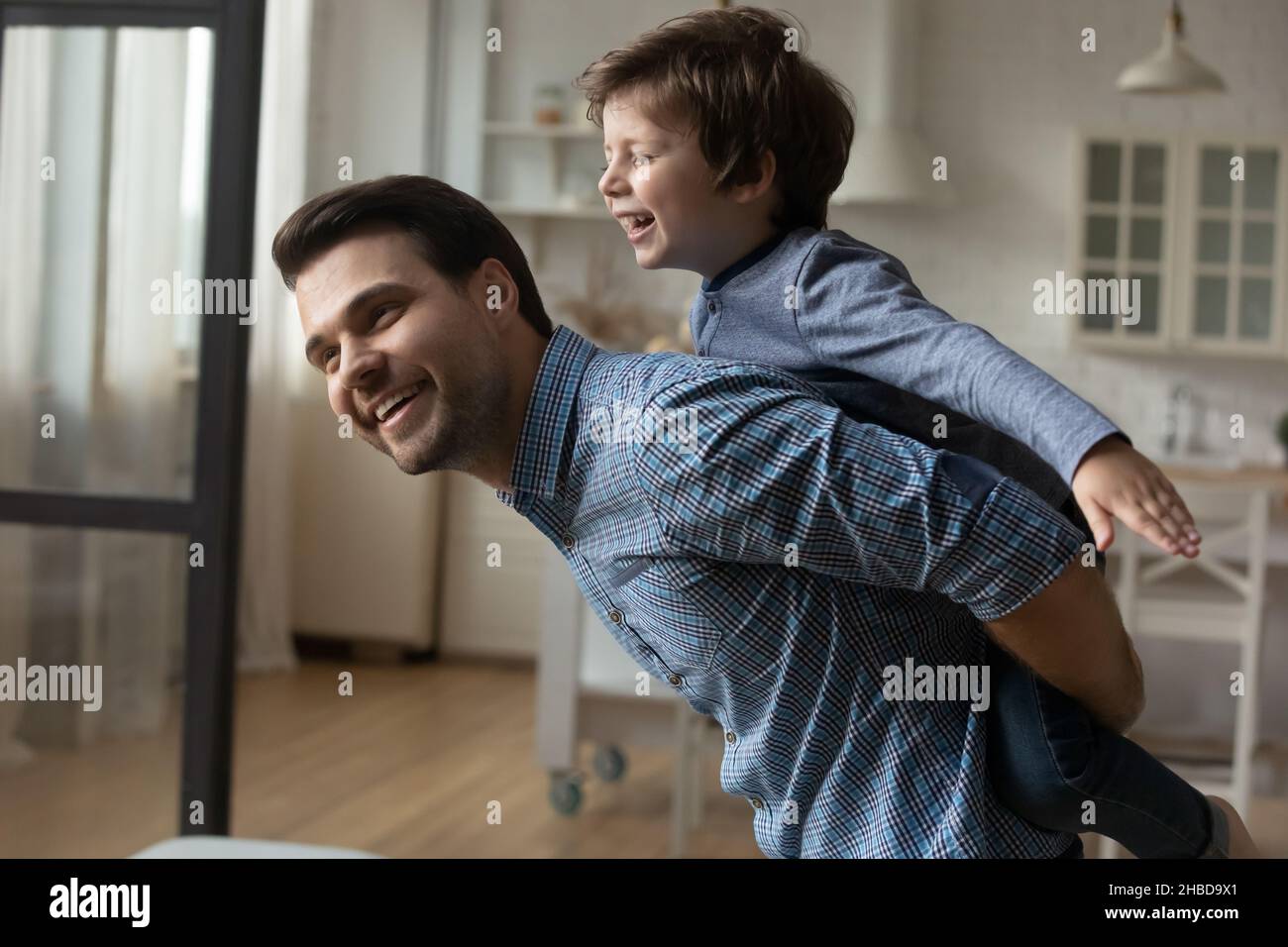 Liebende kaukasischen Vater Piggy Unterstützung kleinen Sohn zu Hause Stockfoto