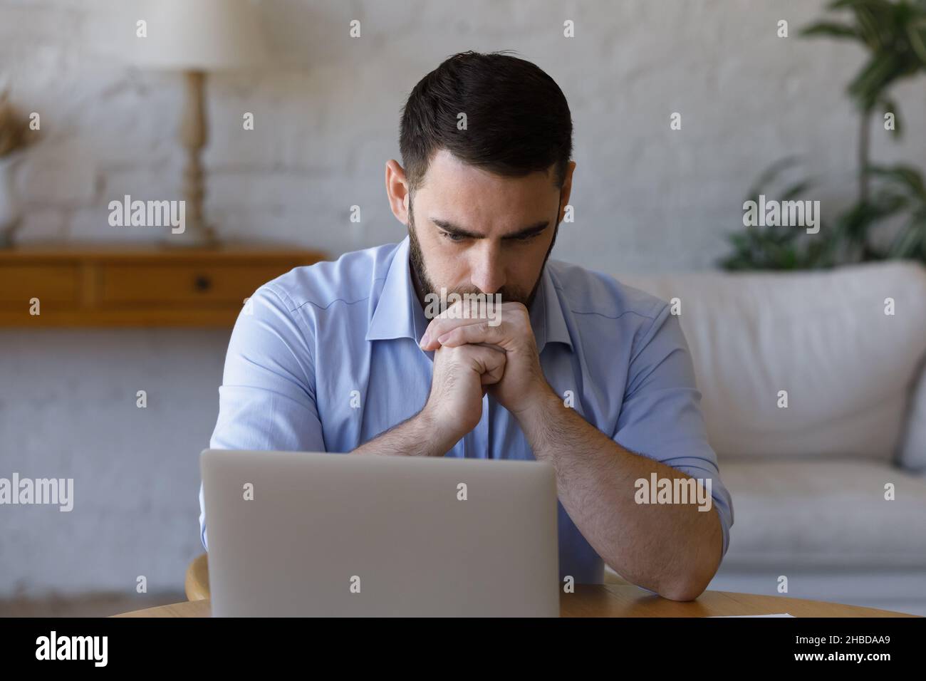 Gestresster junger Geschäftsmann, der auf den Computerbildschirm schaut. Stockfoto