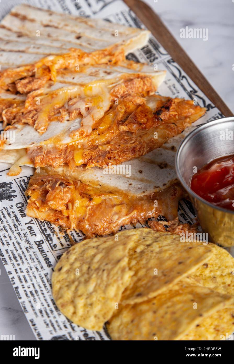 Mexikanisches, würziges Huhn, Tinga quesadillas, serviert mit Limettenkeilen, Salsa und Nachos. Stockfoto