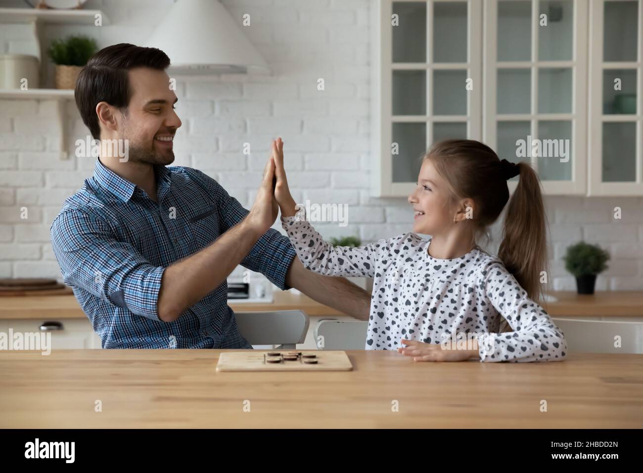 Glücklicher Vater und Tochter geben hohe fünf, Brettspiel spielen Stockfoto