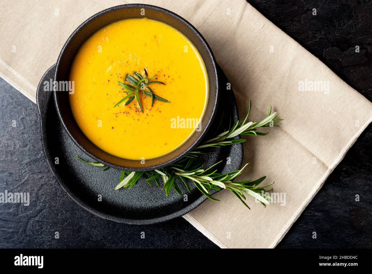Kürbissuppe auf Leinenserviette auf dunklem Hintergrund. Konzept des Essens von saisonalen Lebensmitteln, klimatarische Ernährung. Stockfoto