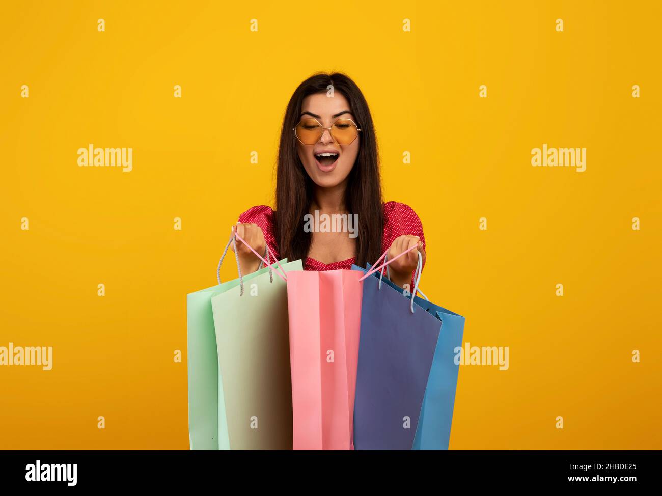 Zufriedener Kunde. Aufgeregt armenische Frau, die in helle Einkaufstaschen schaut, glücklich mit ihren Einkäufen Stockfoto