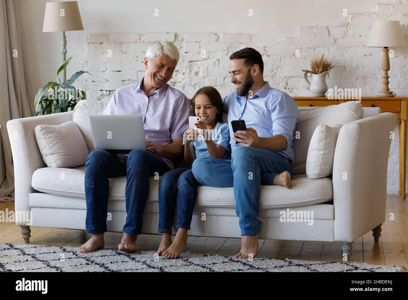Glücklich entspannte Multigenerationenfamilie mit verschiedenen Gadgets. Stockfoto