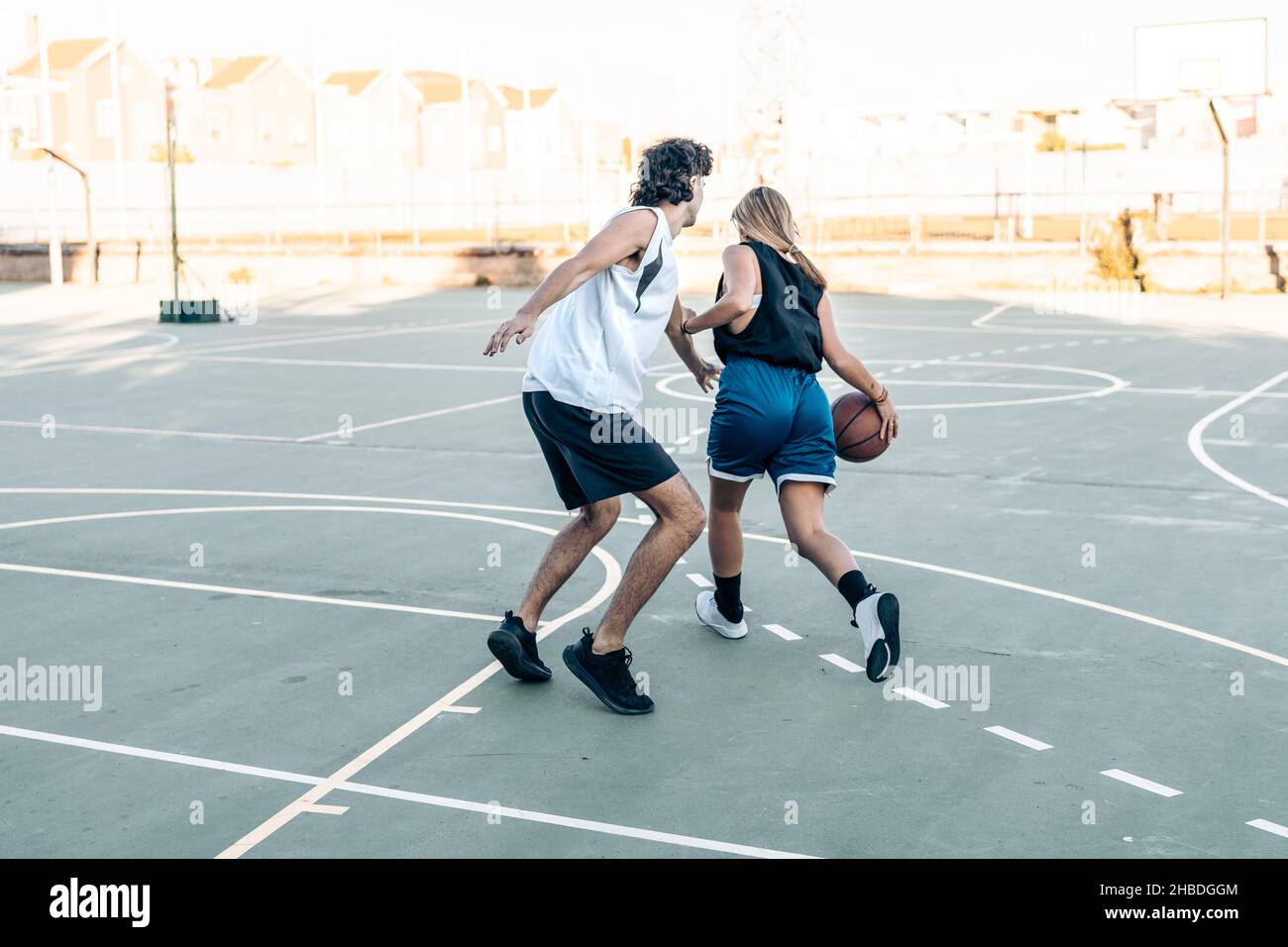 Frau hüpft einen Ball, während sie Basketball auf einem Platz im Freien spielt Stockfoto
