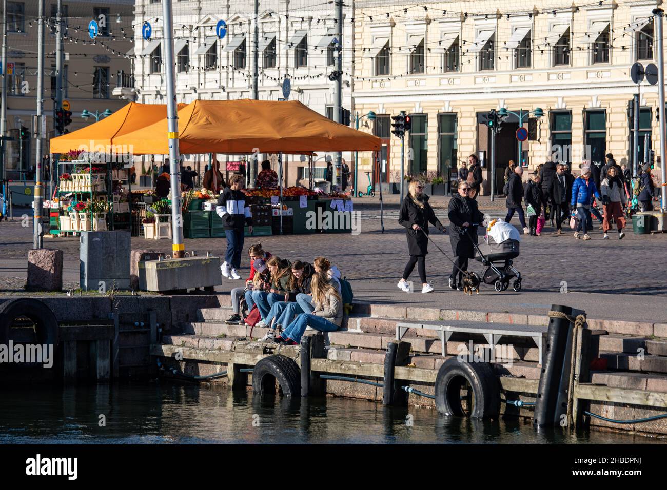 Gruppe junger Frauen oder Teenager, die auf dem Kolera-allas-Dock am Kauppatori oder am Marktplatz in Helsinki, Finnland, sitzen Stockfoto