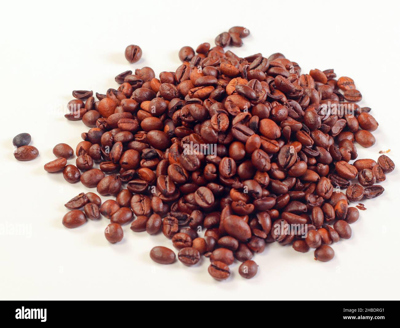 Kaffeebohnen auf weißem Hintergrund isoliert. Haufen gerösteter Kaffeebohnen auf weißem Tisch verstreut. Stockfoto
