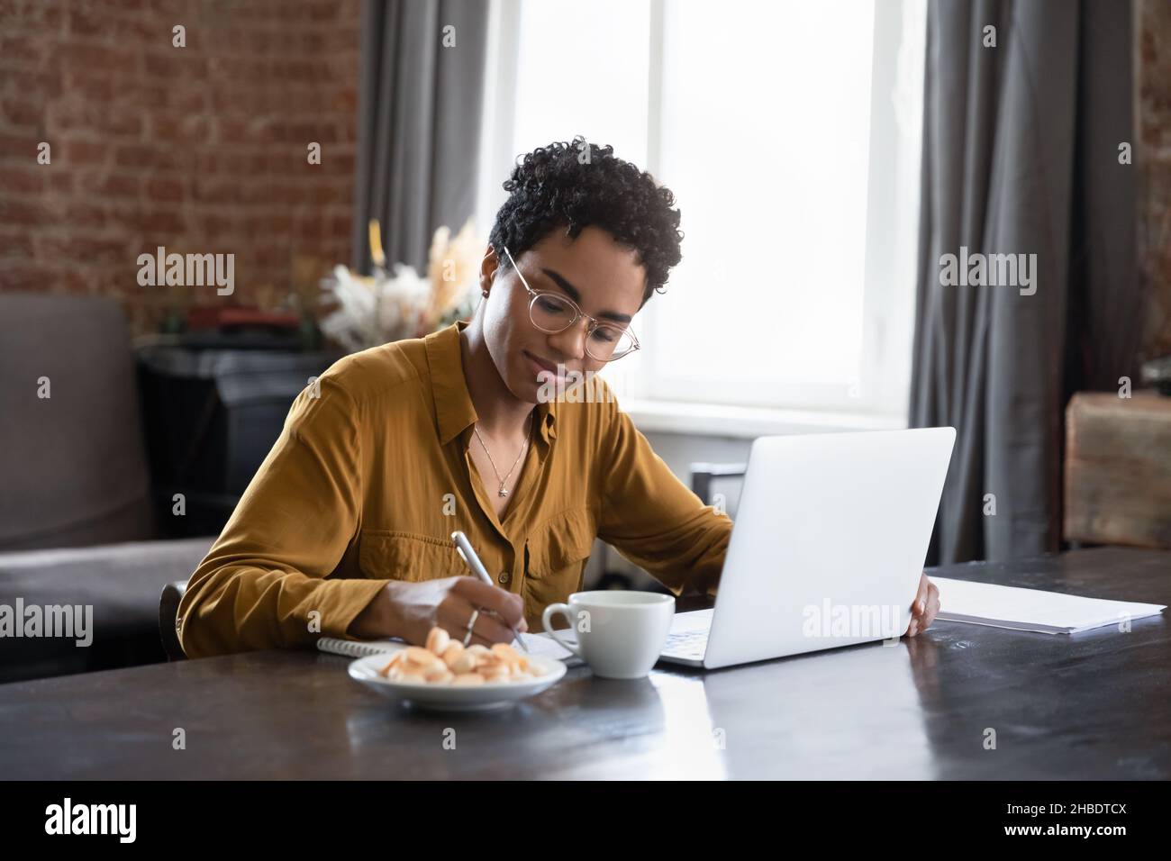 Glückliche intelligente junge afroamerikanische Frau, die zu Hause studiert. Stockfoto