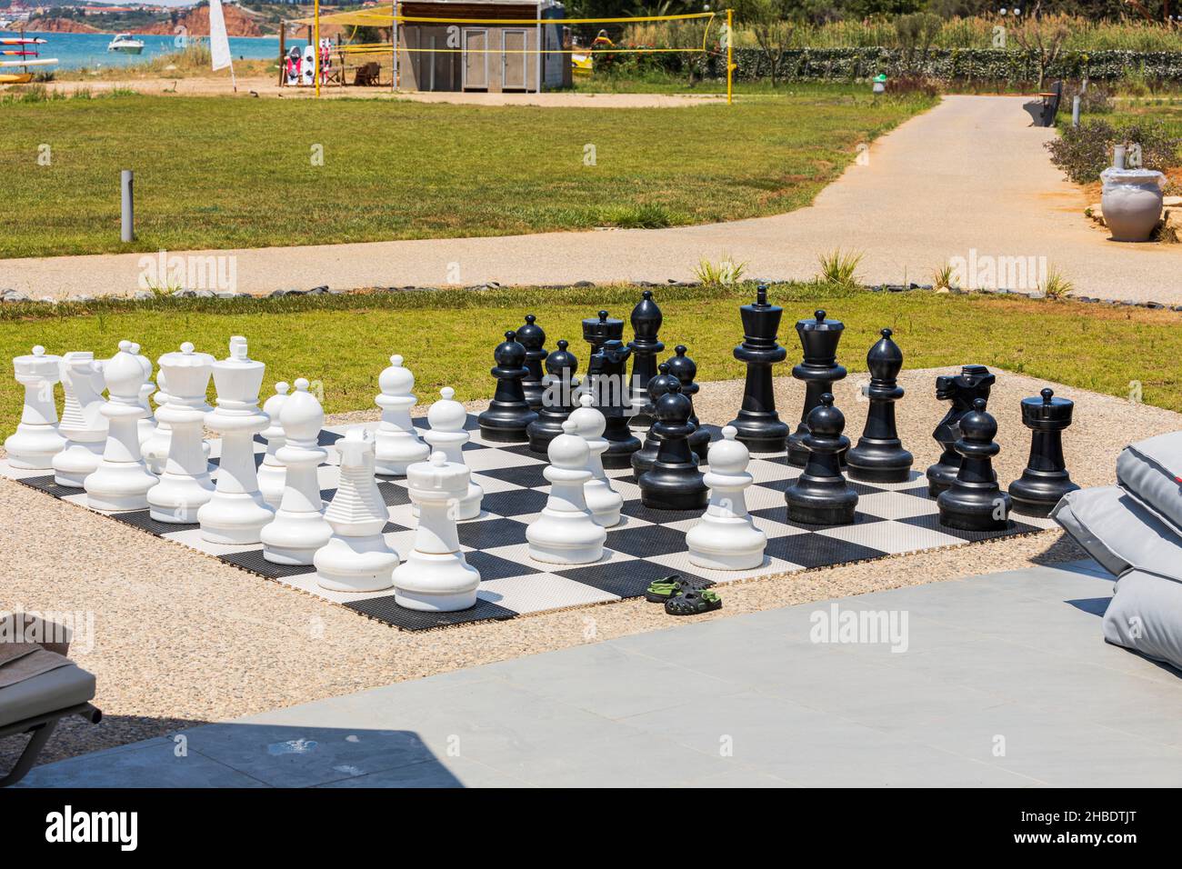 Wunderschöne Aussicht auf das Schachbrett mit riesigen schwarz-weißen Schachfiguren zum Spielen im Freien am Strand. Griechenland. Stockfoto