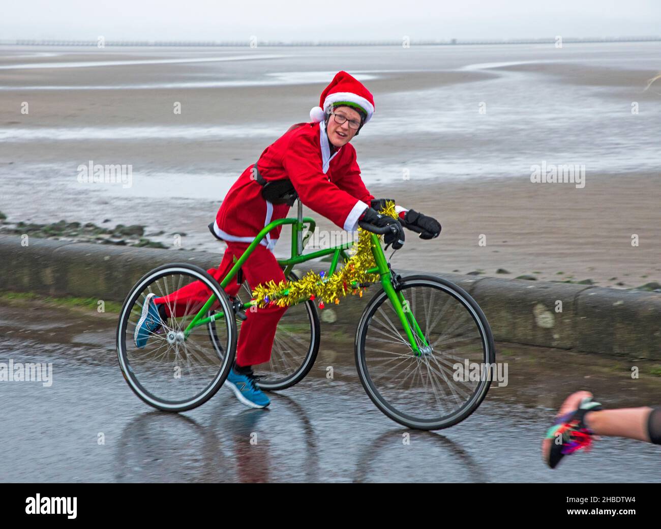 Silverknowes Promenade, Edinburgh, Santa Half Marathon neben 7k und 14k, Schottland, Großbritannien. 19th. Dezember 2021. Ein sehr trister Tag mit konstantem Nieselregen und 4 Grad Celsius für den „Blast Running SANTA DASH“ hielt diese glücklichen Seelen nicht davon ab, ihren Marathon-Wettkampf im Dezember zu genießen. Im Bild Findlay Menzies im Wettbewerb mit seinem adaptierten Trike. Credit: Arch White Stockfoto Silverknowes Promenade, Edinburgh, Santa Half Marathon neben 7k und 14k, Schottland, Großbritannien. 19th. Dezember 2021. Ein sehr trister Tag mit konstantem Nieselregen und 4 Grad Celsius für den „Blast Running SANTA DASH“ hielt diese glücklichen Seelen nicht davon ab, ihren Marathon-Wettkampf im Dezember zu genießen. Im Bild Findlay Menzies im Wettbewerb mit seinem adaptierten Trike. Credit: Arch White Stockfoto