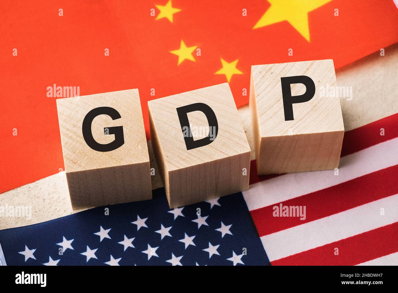 Holzwürfel mit dem Text auf dem Hintergrund der Flaggen von China und Amerika, das Konzept zum Thema des Vergleichs des BIP der USA und Chinas Stockfoto