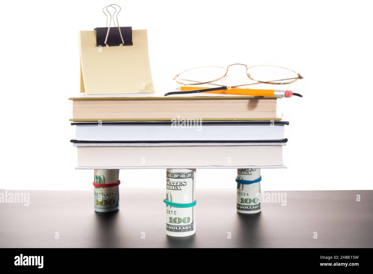 Bücher sind auf dem Geld. Sticker, Bleistift und Brille auf Büchern. Banknoten des Finanziers. Stockfoto