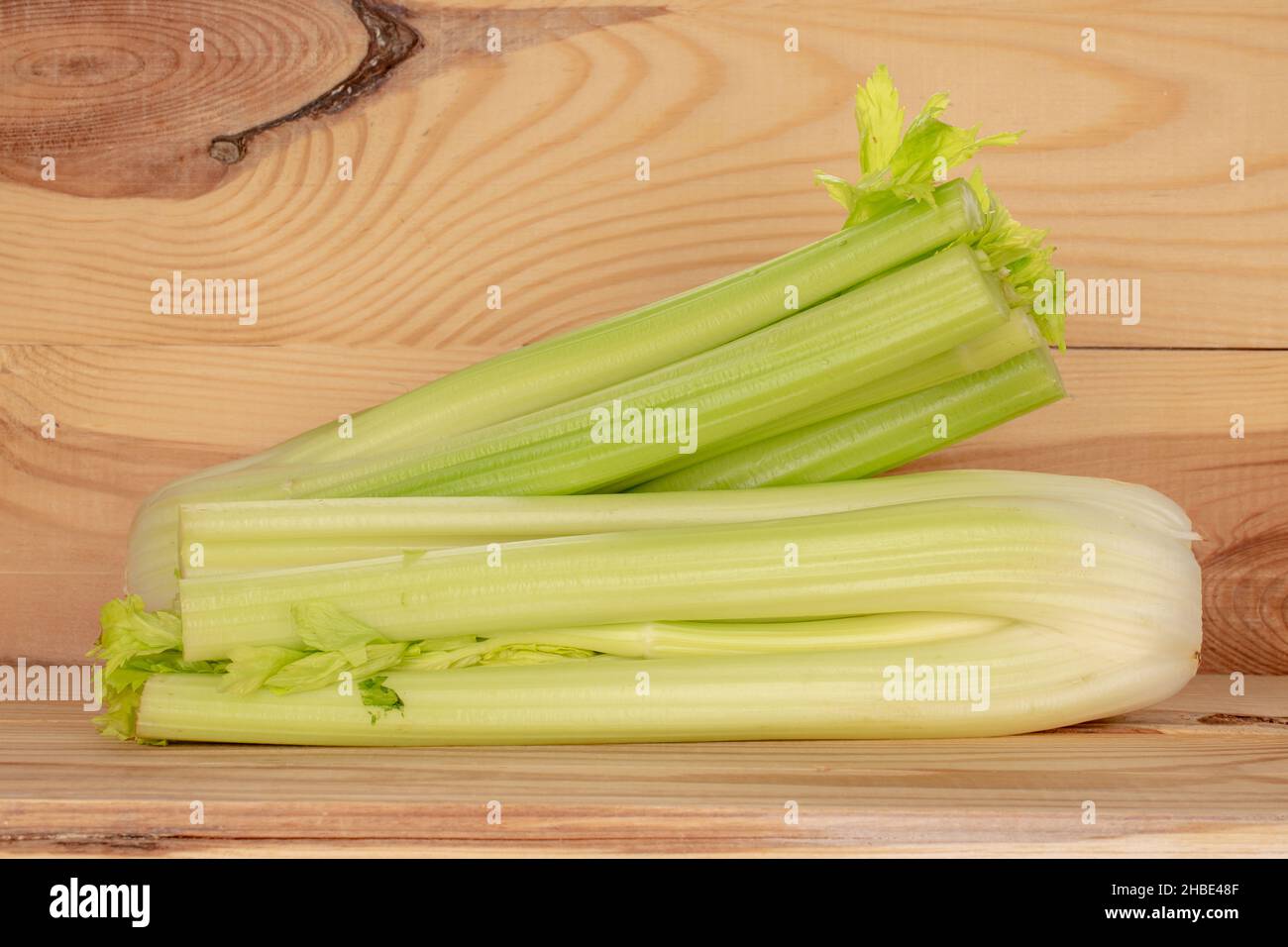 Zwei hellgrüne, natürliche, saftige Selleriestiele, Nahaufnahme, vor einem Hintergrund aus natürlichem Holz. Stockfoto