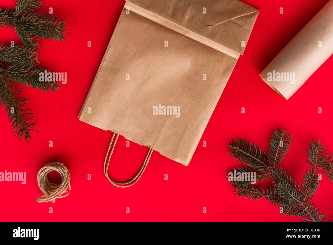 Weihnachten und Neujahr festlich Flat Lay imitieren Geschenke Herstellung, Vorbereitung und Verpackung in Kraftpapier-Paket auf rotem Hintergrund. Stockfoto