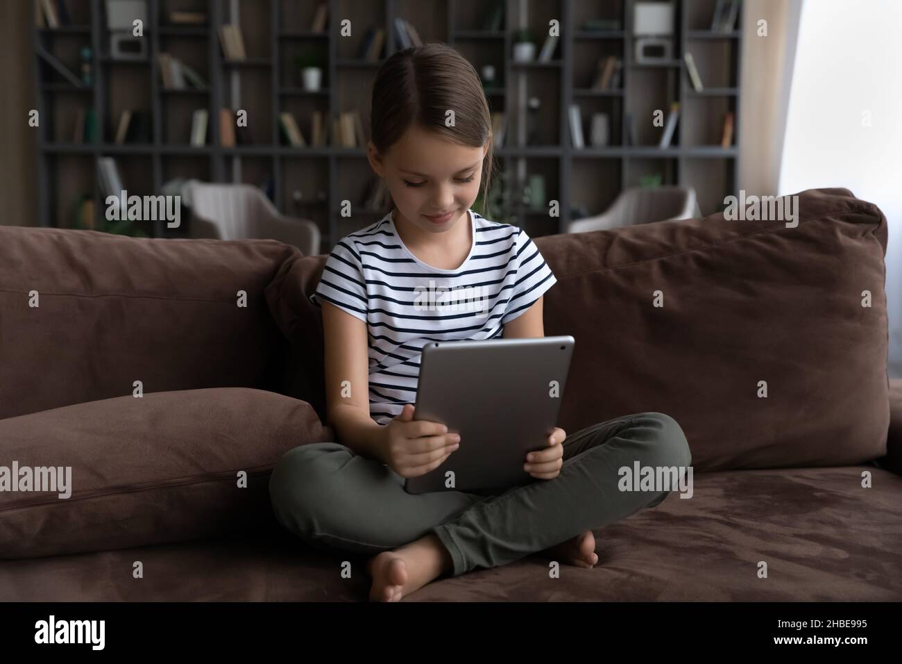 Neugierige Mädchen preteen sitzen auf dem Sofa allein halten digitale Pad Stockfoto