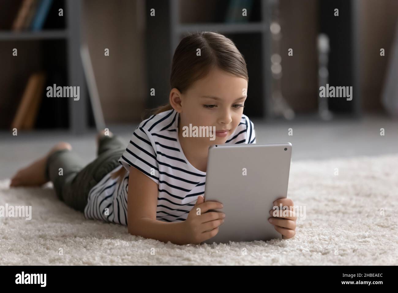 Happy Tween Mädchen Kind liegt auf dem Teppich mit digitalen Touchpad Stockfoto
