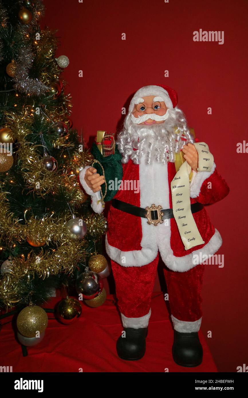 Weihnachtsmann mit einem weißen langen Bart, rotem Hut, Brille und einer grünen Tasche voller Geschenke, Weihnachtsmann und Weihnachtsbaum mit Dekoration, Weihnachtsmann Kind Stockfoto