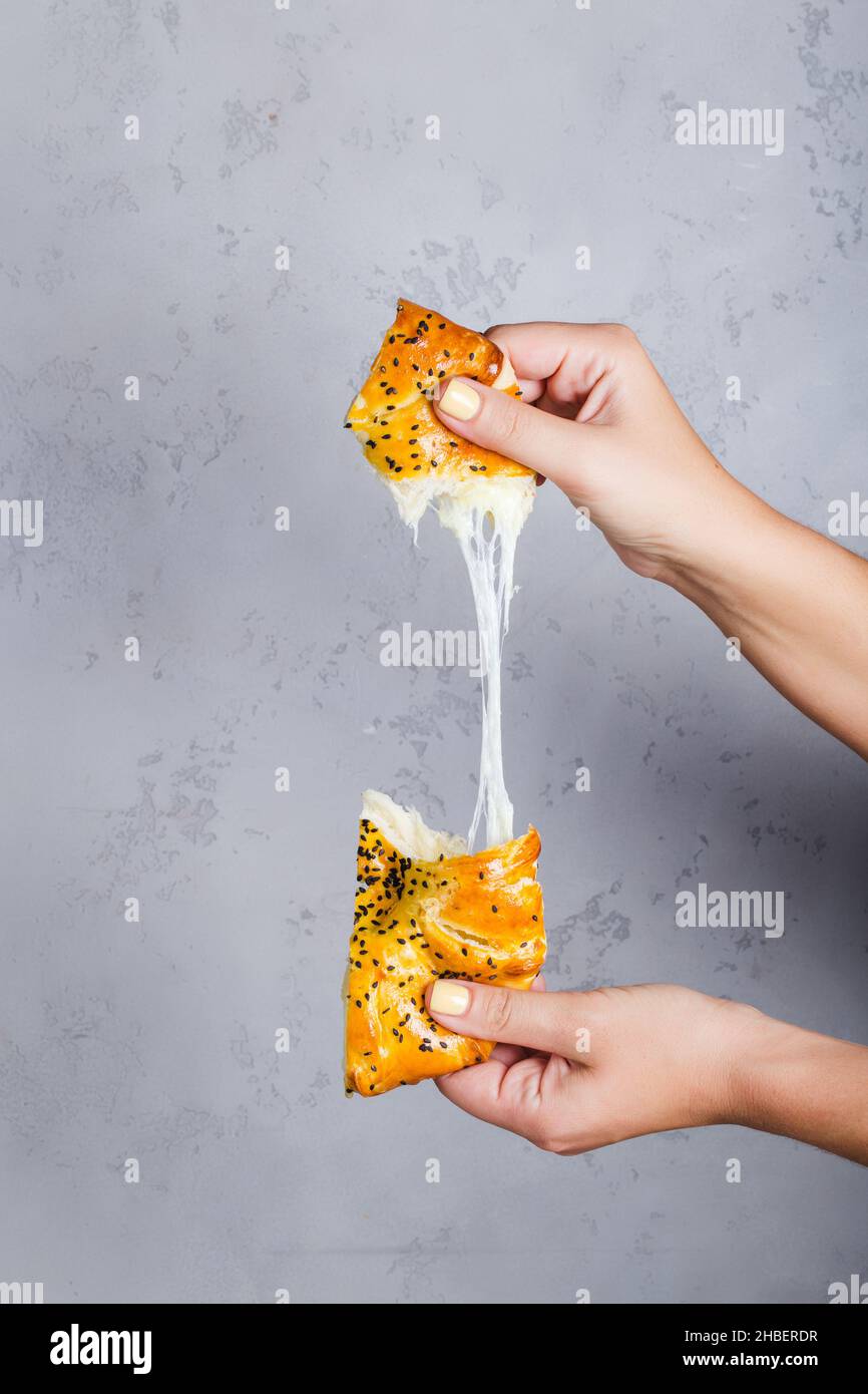Frau Hände nimmt usbekische nationale Lebensmittel Tandyr Brot Lepeshka mit Käse auf grauem Hintergrund Stockfoto