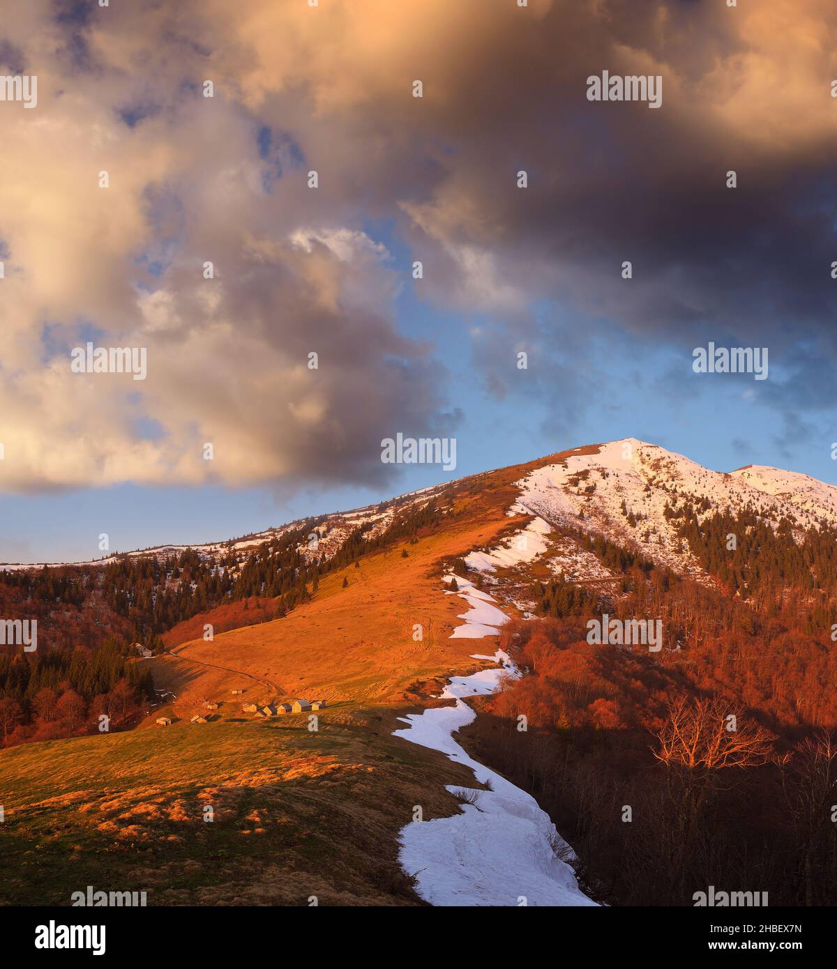 Frühlingslandschaft mit Holzhäusern in den Bergen. Die Besiedlung der Hirten. Licht der untergehenden Sonne Stockfoto