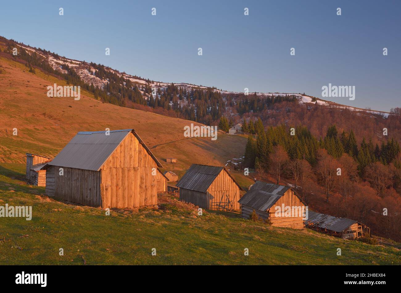 Frühlingslandschaft mit Holzdorf von Hirten in den Bergen. Licht der untergehenden Sonne. Karpaten, Ukraine, Europa Stockfoto