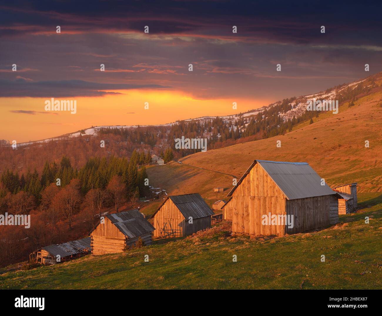 Frühlingslandschaft mit Holzdorf von Hirten in den Bergen. Licht der untergehenden Sonne Stockfoto