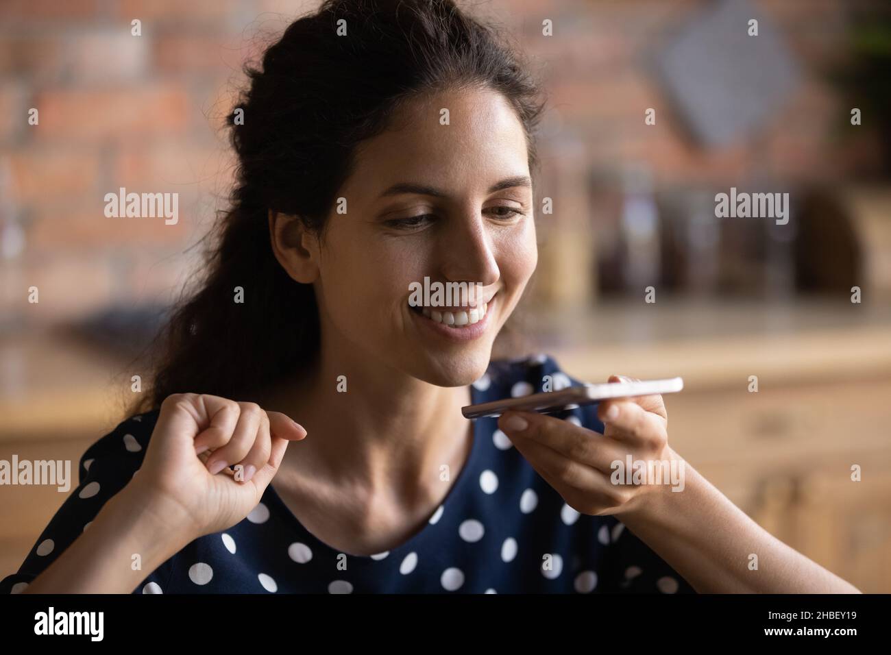 Fröhliche junge hispanische Frau, die Voicemail sendet. Stockfoto
