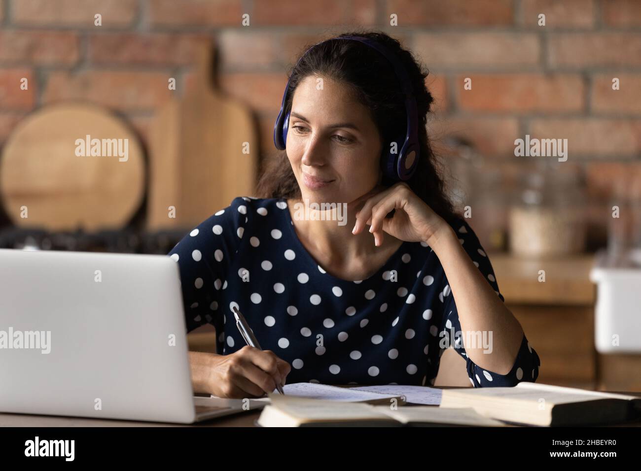 Glückliche interessierte junge hispanische Frau, die entfernt studiert. Stockfoto