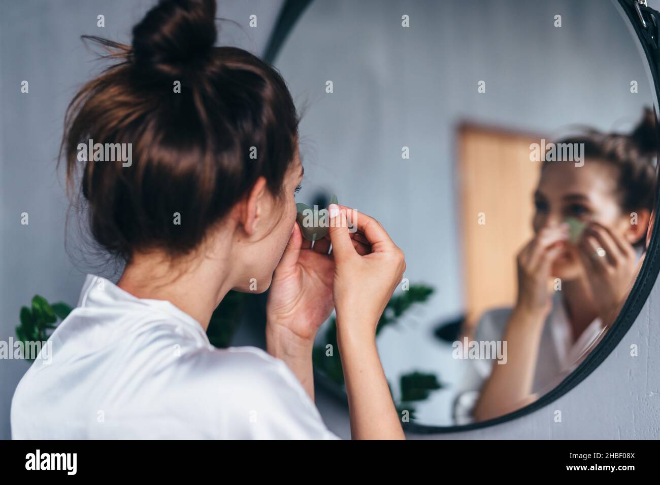 Die junge Frau kümmert sich zu Hause um ihre Gesichtshaut. Stockfoto