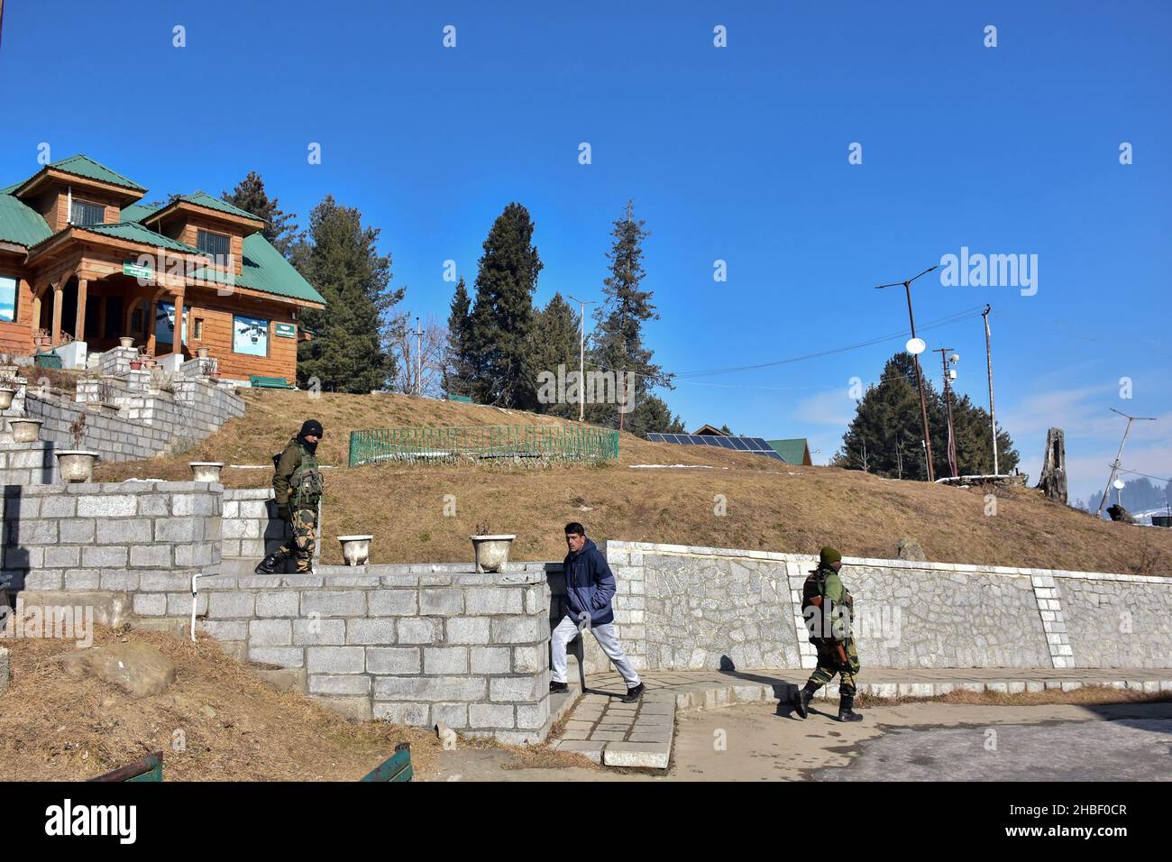 Gulmarg, Indien. 19th Dez 2021. Ein Mann geht nach oben, während paramilitärische Truppen an einem kalten Wintertag in einem berühmten Skigebiet in Gulmarg, etwa 55kms von Srinagar entfernt, patrouillieren. Kredit: SOPA Images Limited/Alamy Live Nachrichten Stockfoto